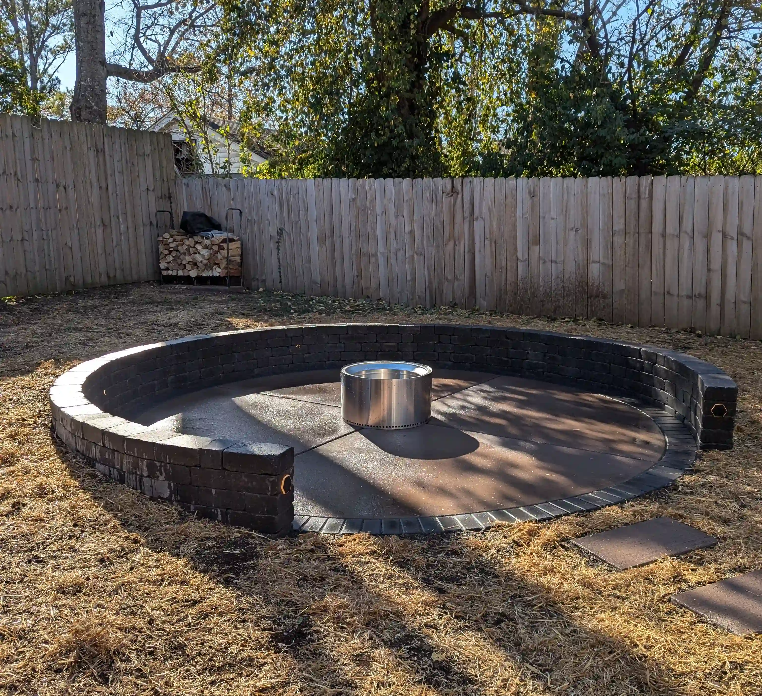 circular concrete firepit area surrounded by a retaining wall made from large stone