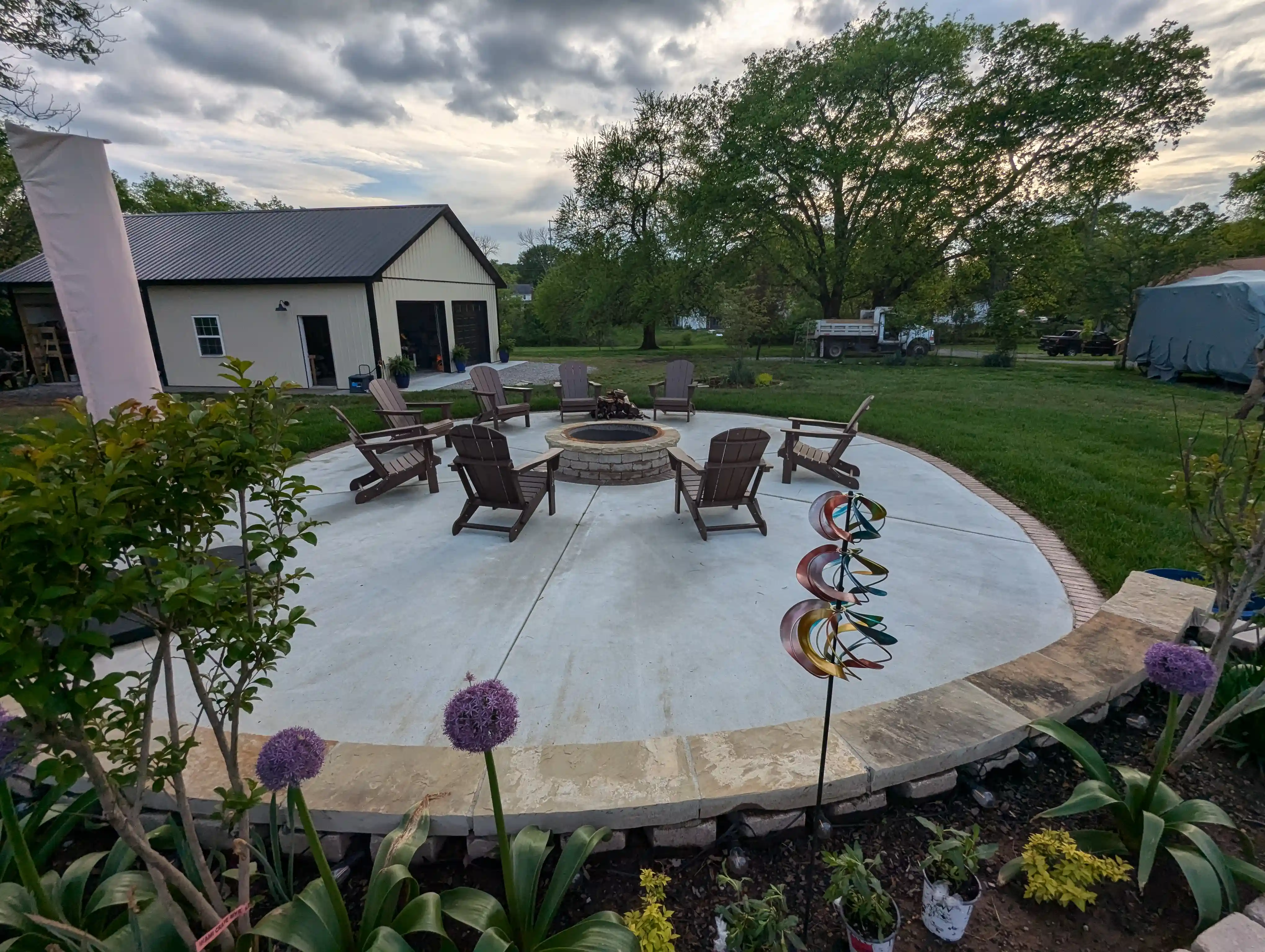 beautiful garden bed surrounding a large firepit area with multiple chairs