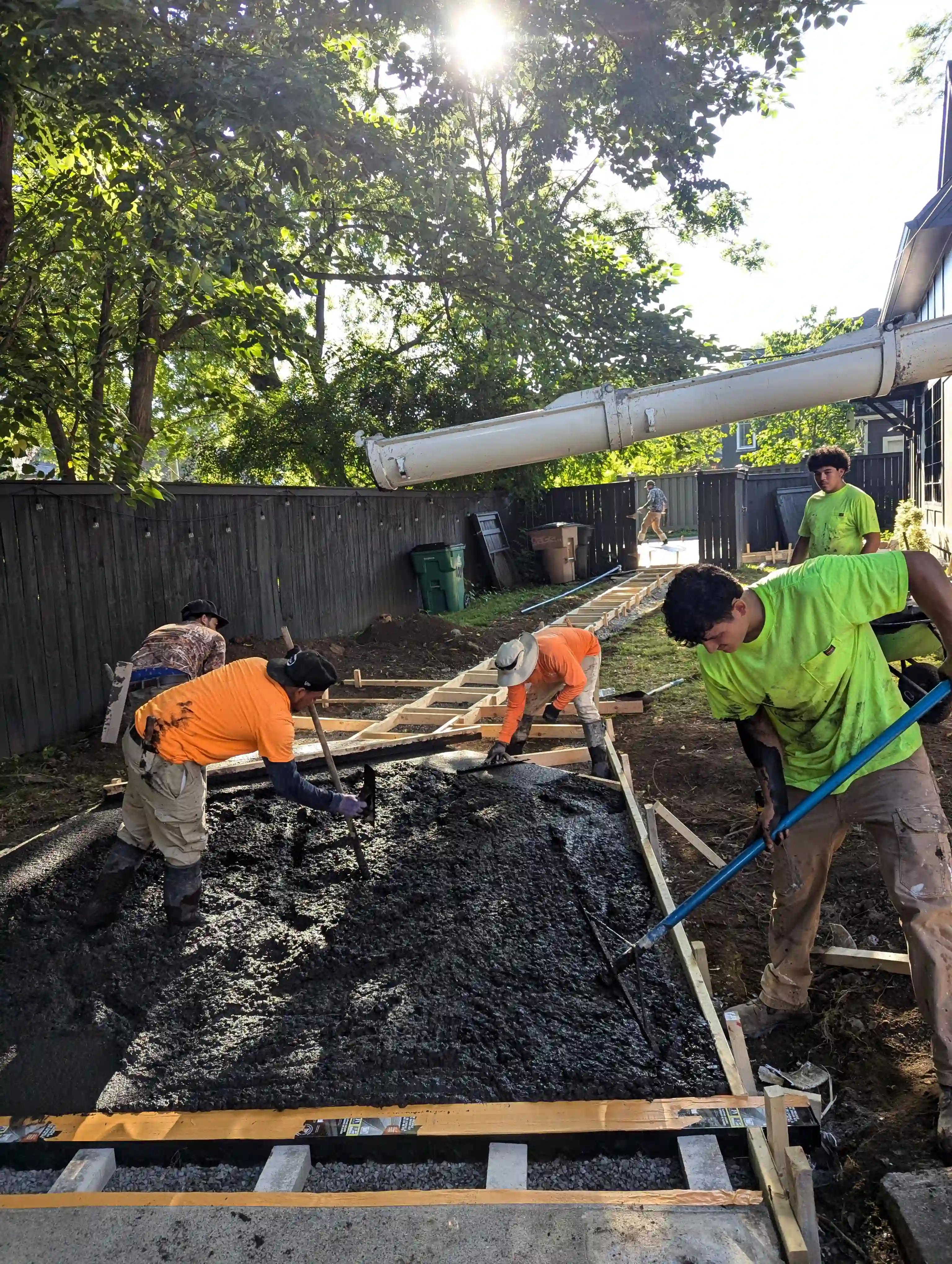 men working with a concrete truck to build a sidewalk