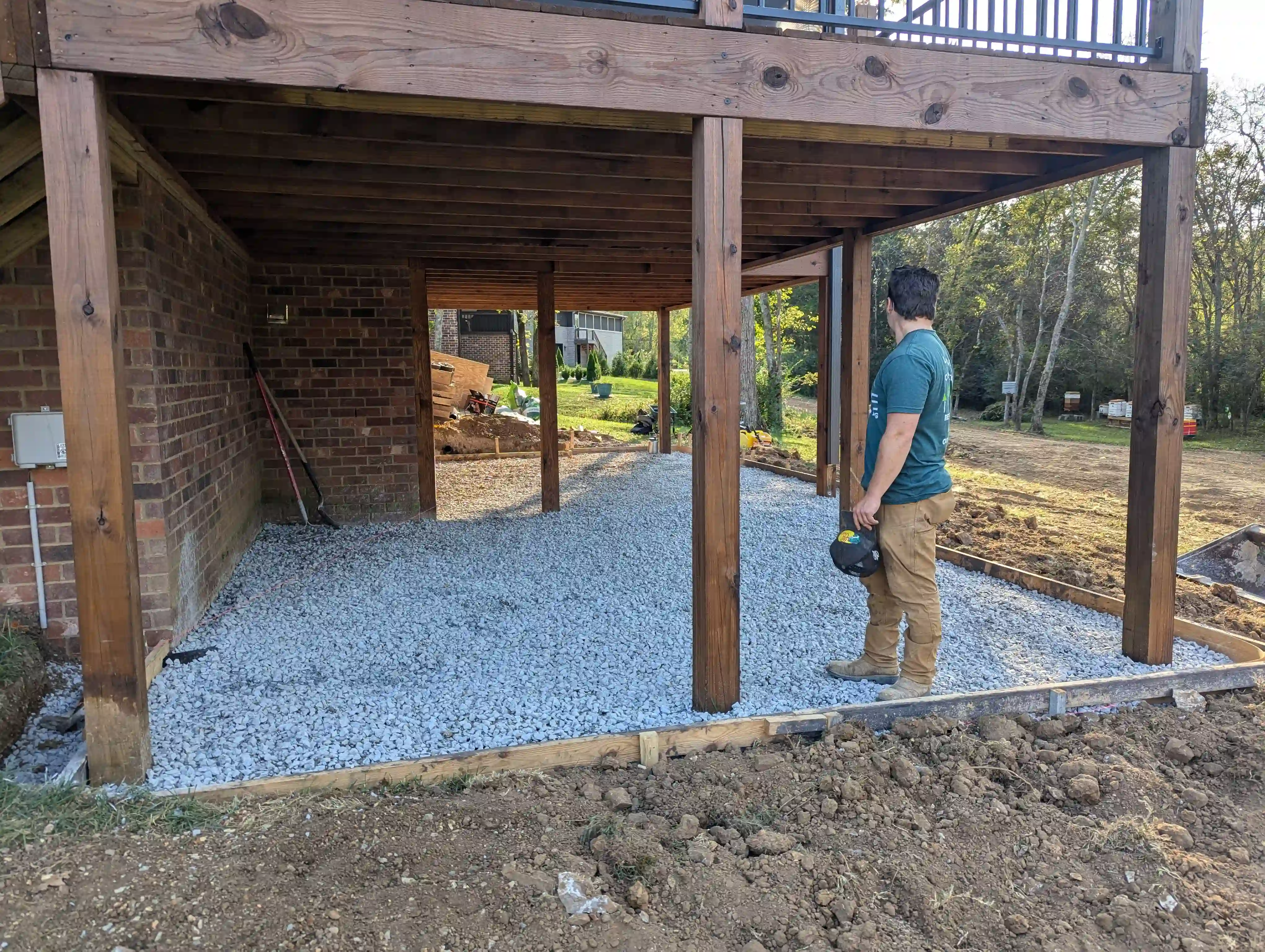 a man standing on gravel underneath a large wooden porch