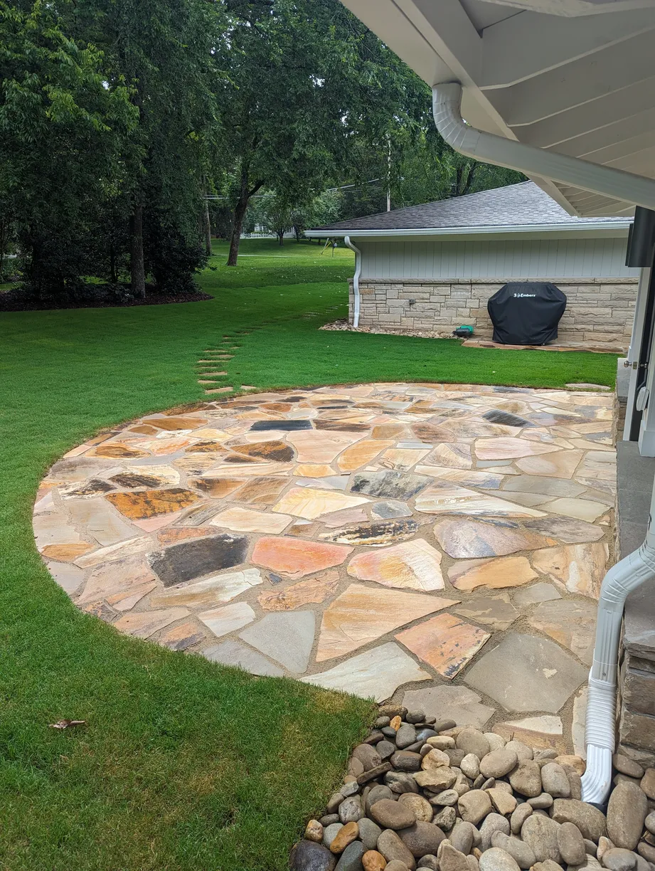 larde rounded flagstone patio with stepping stones leading out of the frame