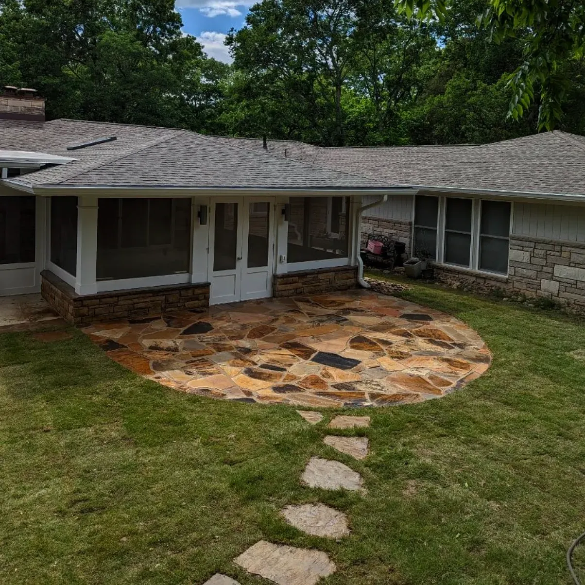 a backyard with a circular flagstone patio right outside of the back door