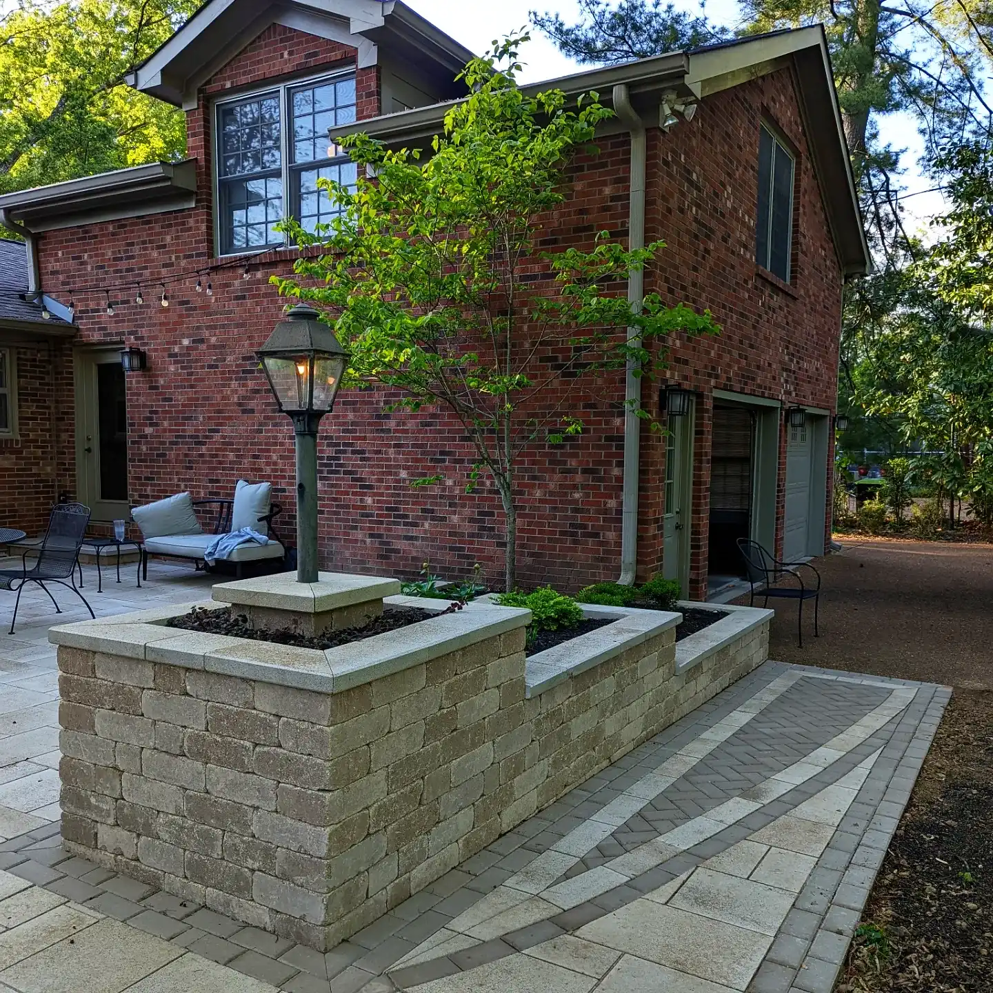 a red brick home with a three tiered garden bed featuring a lamp post 