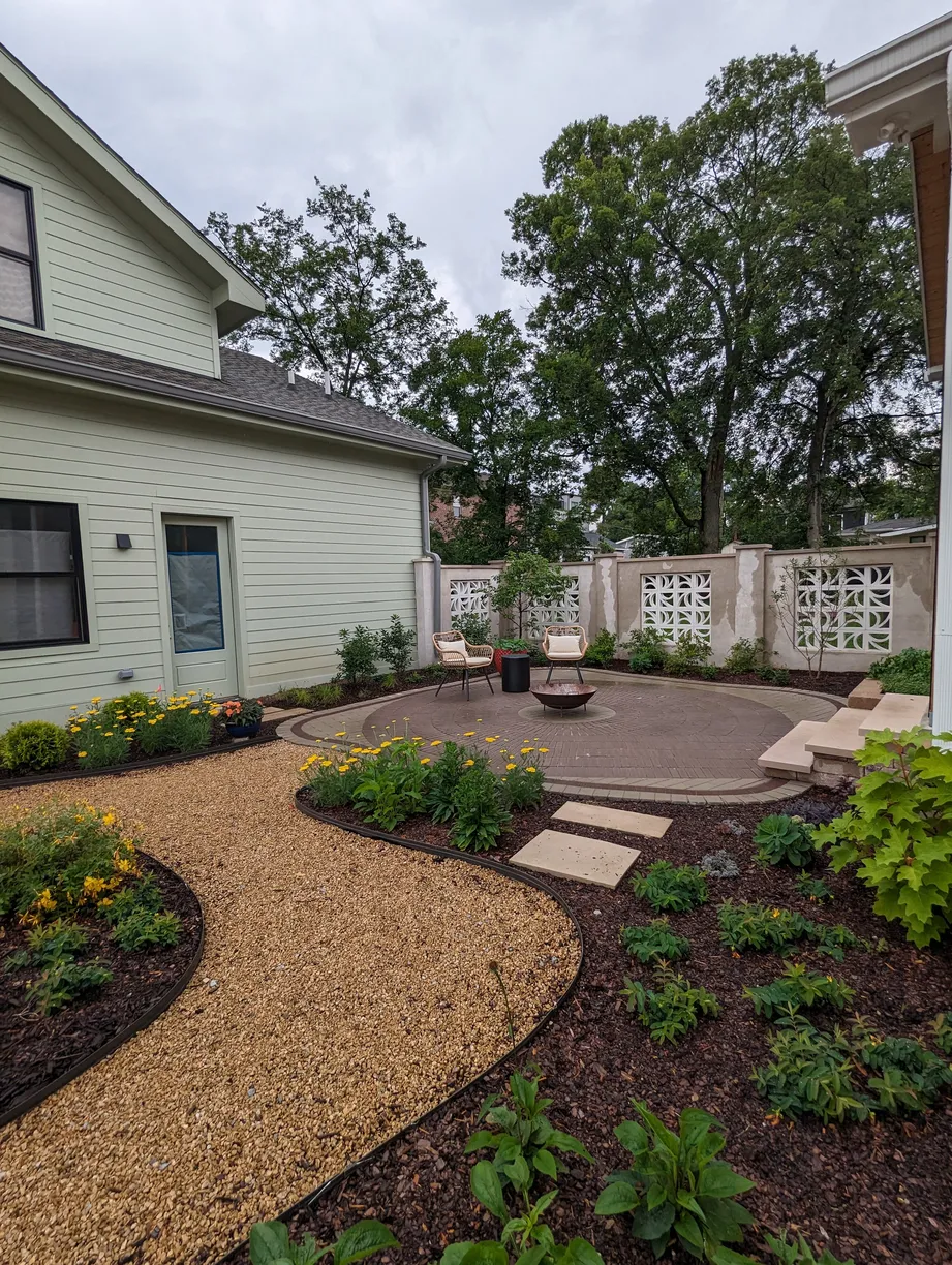 concrete patio outside of a screened in porch surrounded by garden beds with plants