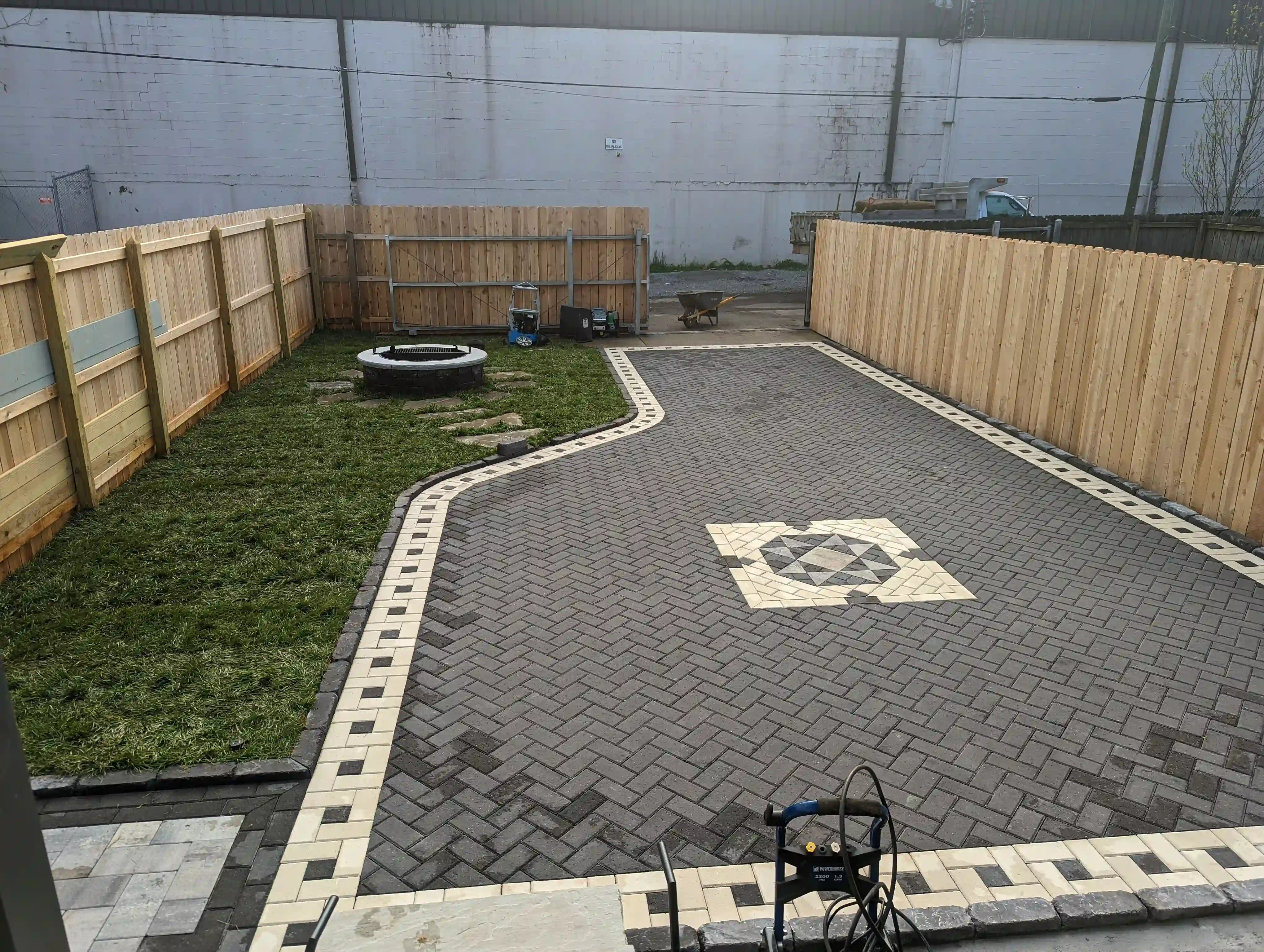 intricate grey and white paver patio with unique design in a small backyard