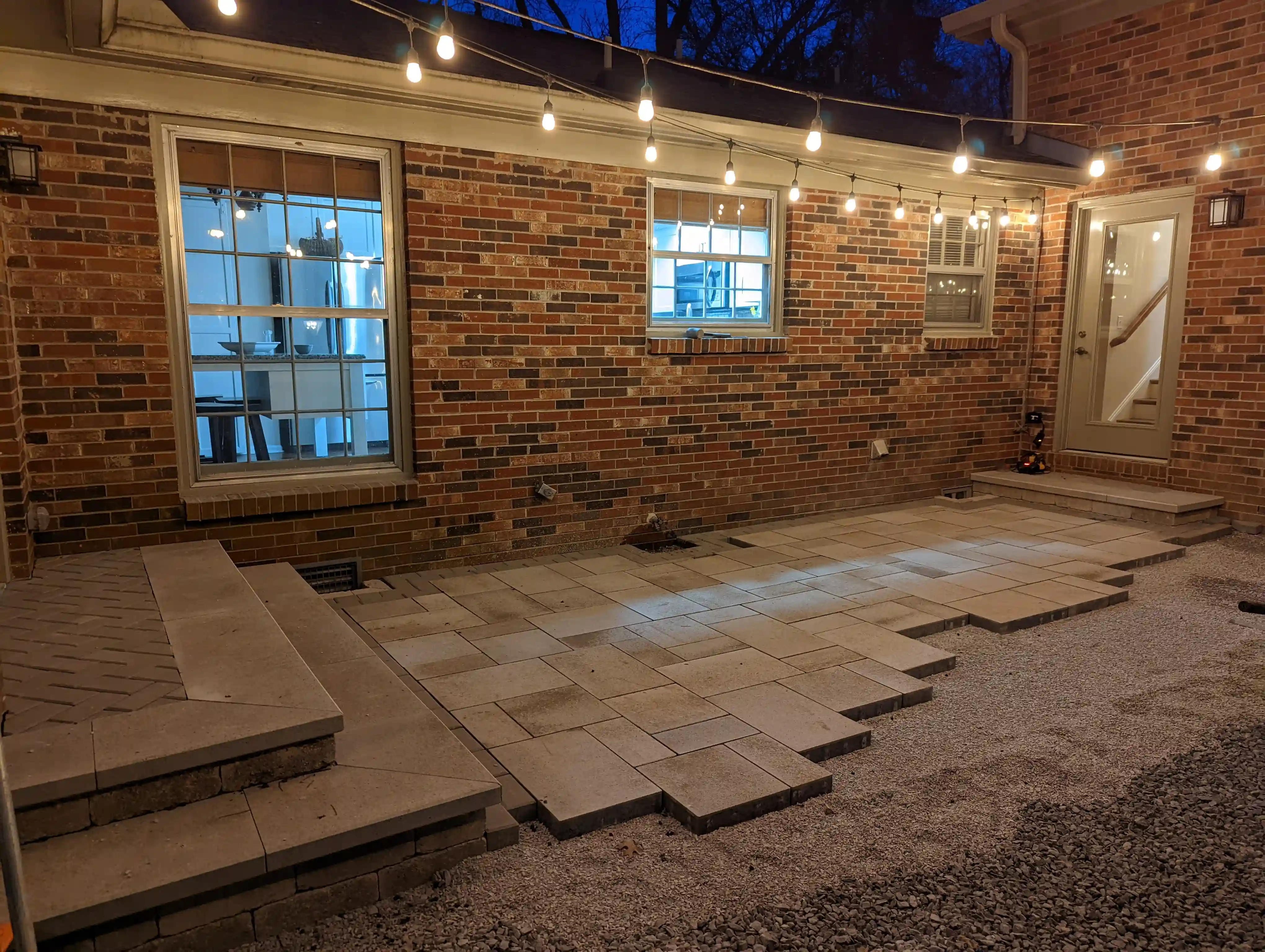 progress picture of a backyard at night with an unfinished paver patio