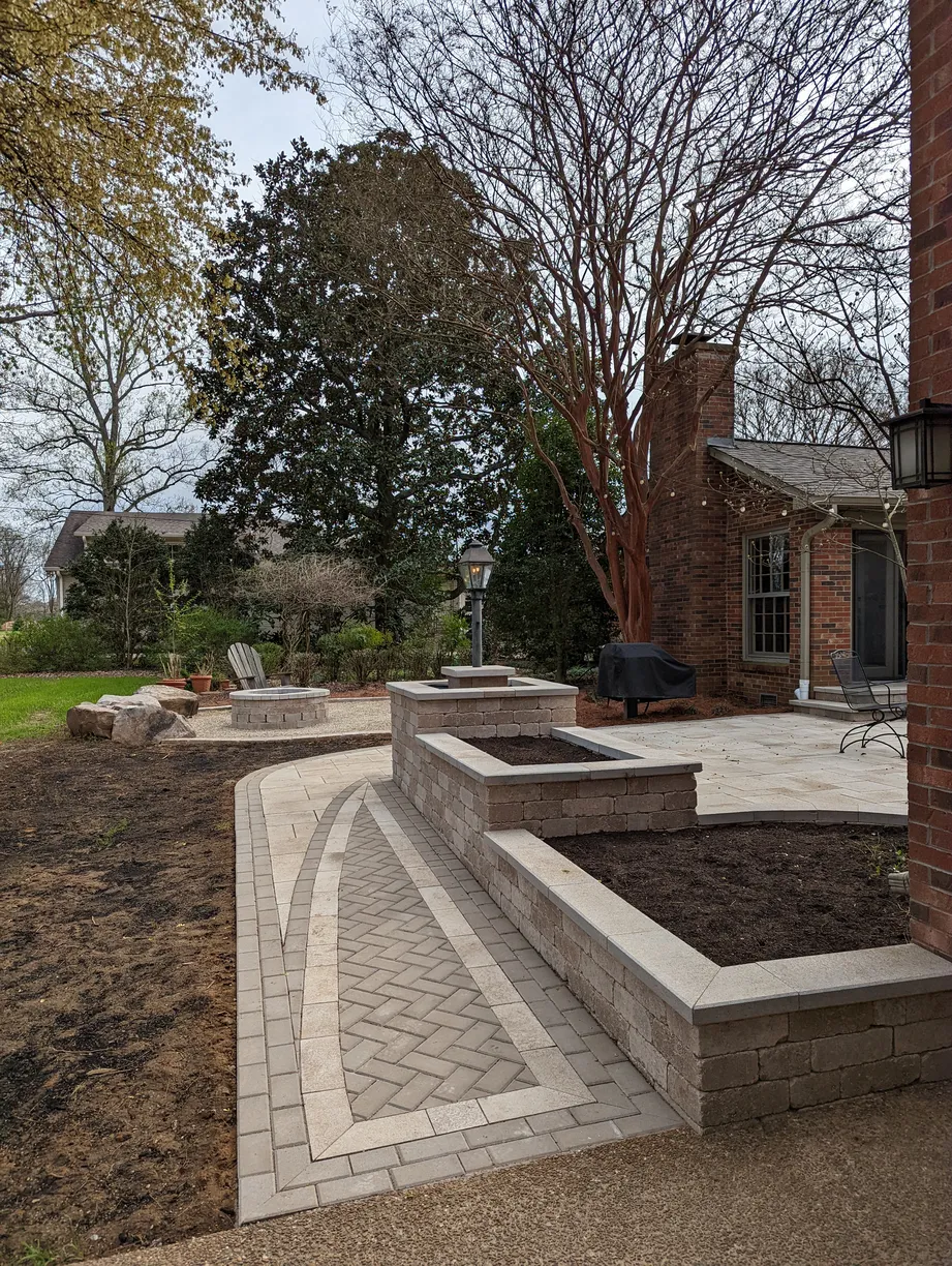 completed paver walkway with intricate design featuring stone garden beds and firepit