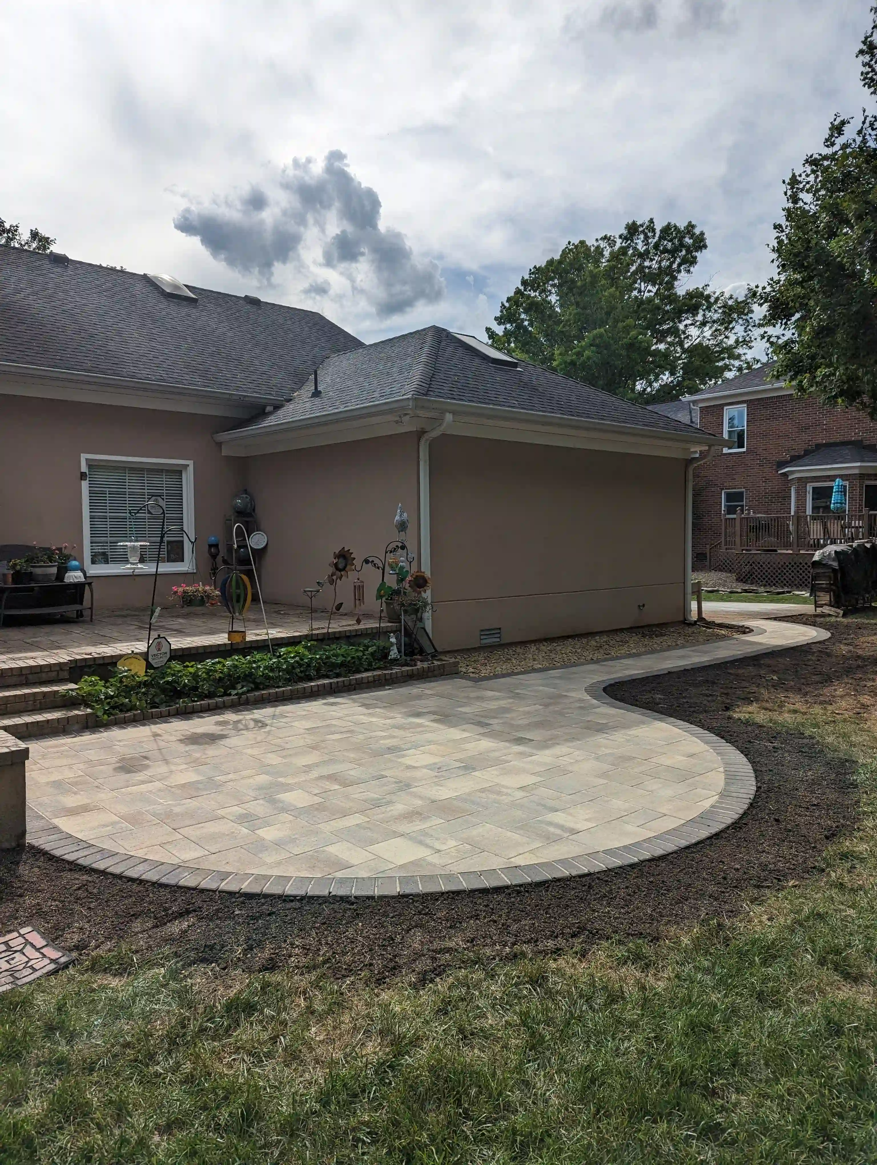 paver walkway leading from the side of the house to a rounded paver patio