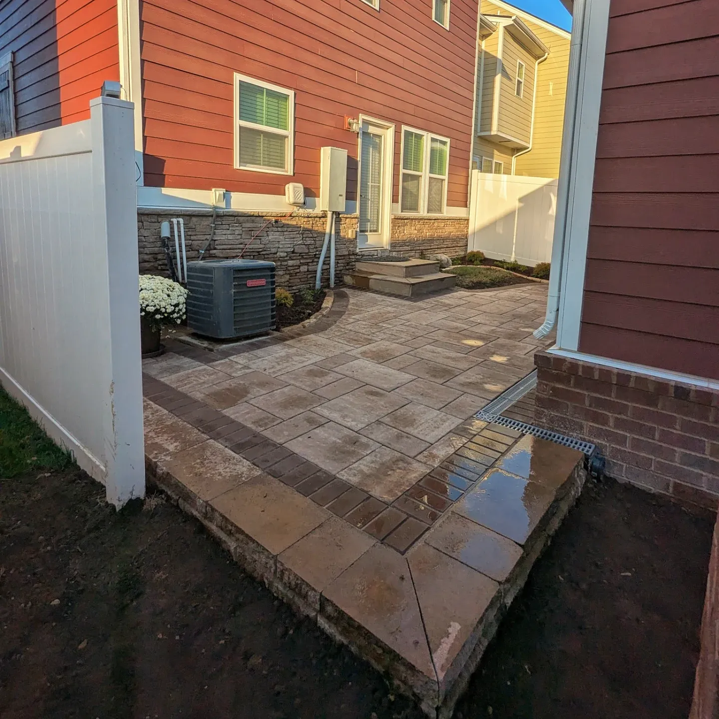 earth colored wet paver patio in a small backyard