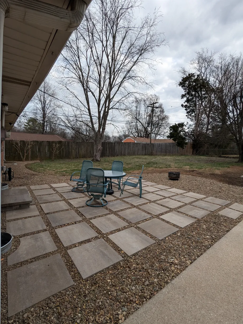 large paver and gravel patio with a blue table and four blue chairs