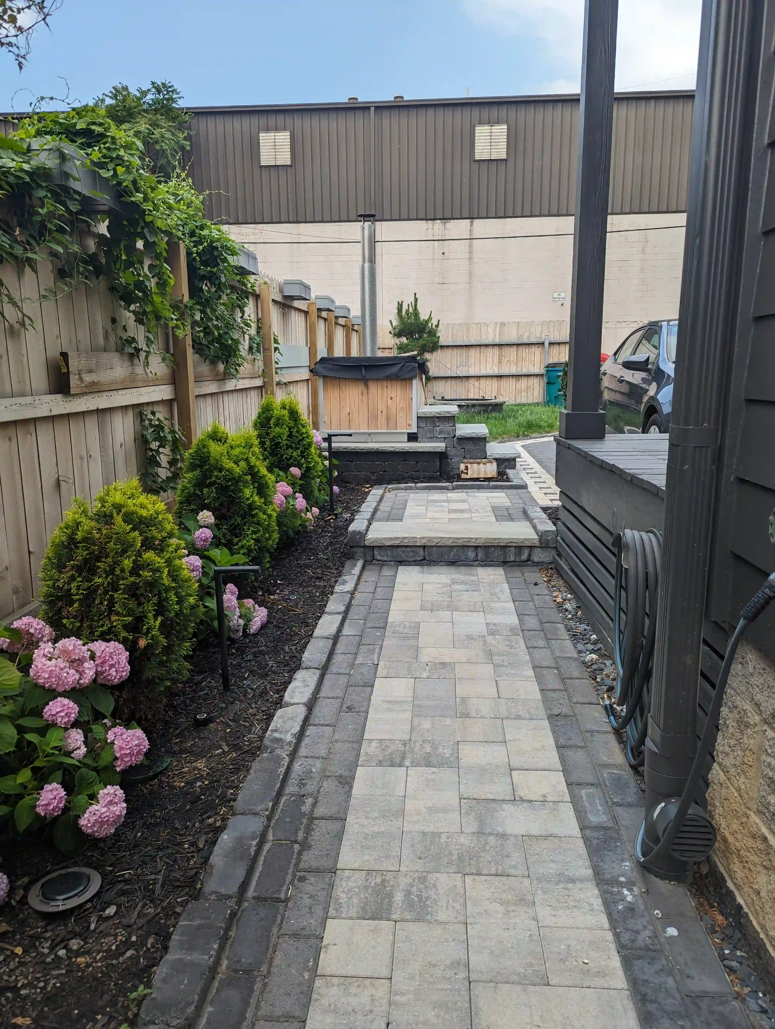 small dark and light grey paver walkway. next to it there are flowers planted in mulch