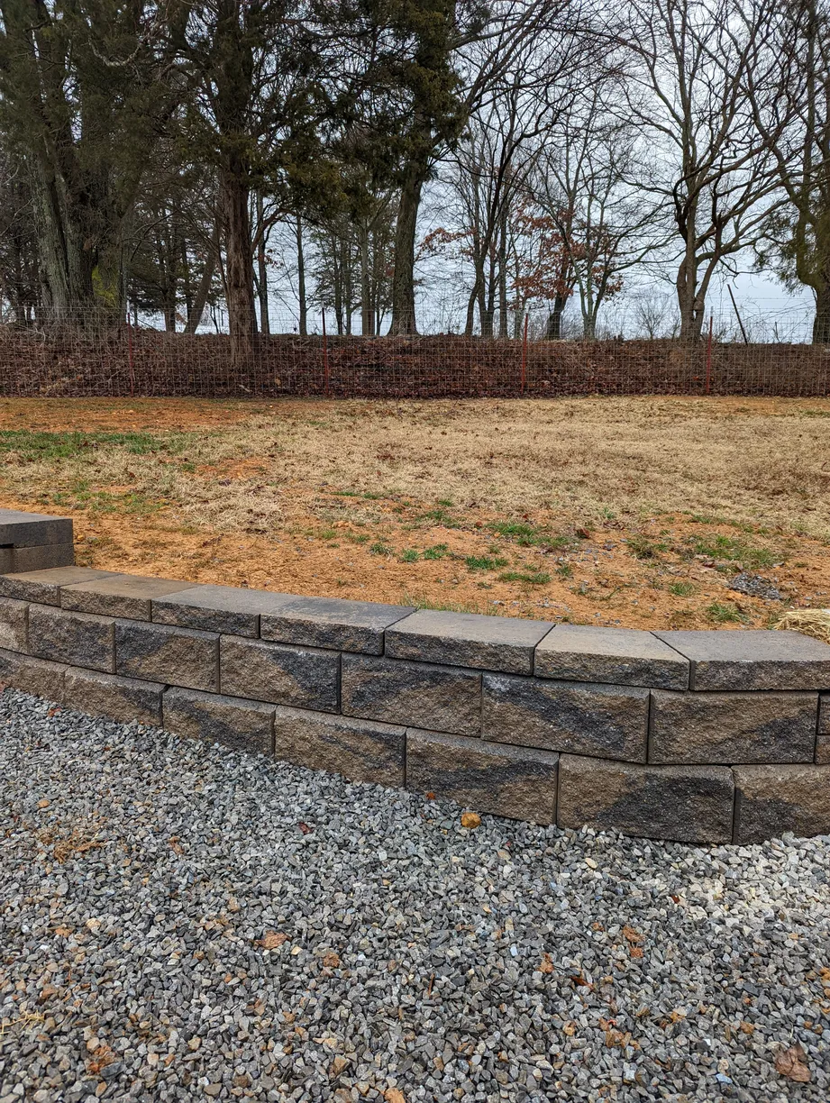 retaining wall with premium stone seperating the lawn and gravel driveway