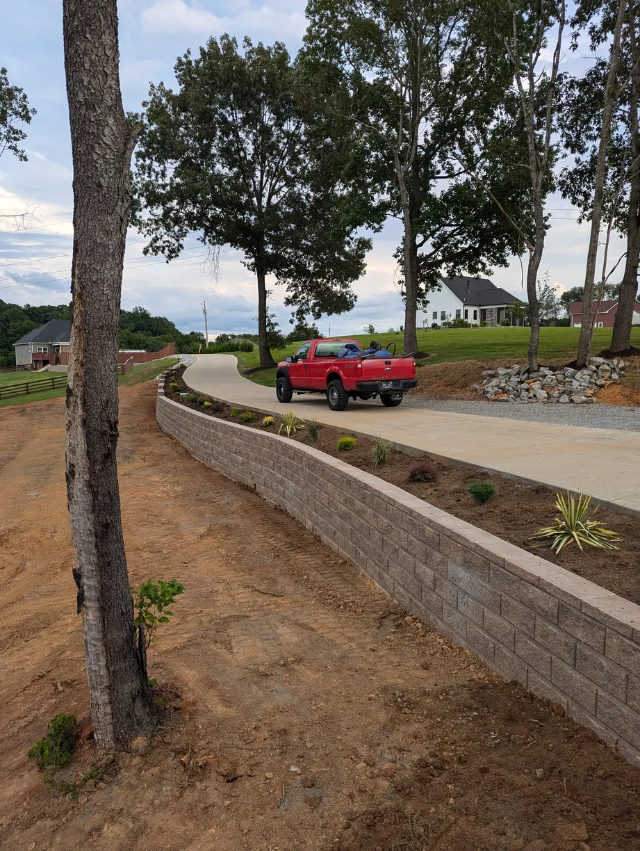 red car perched ontop of a driveway with a newly built retaining wall underneath