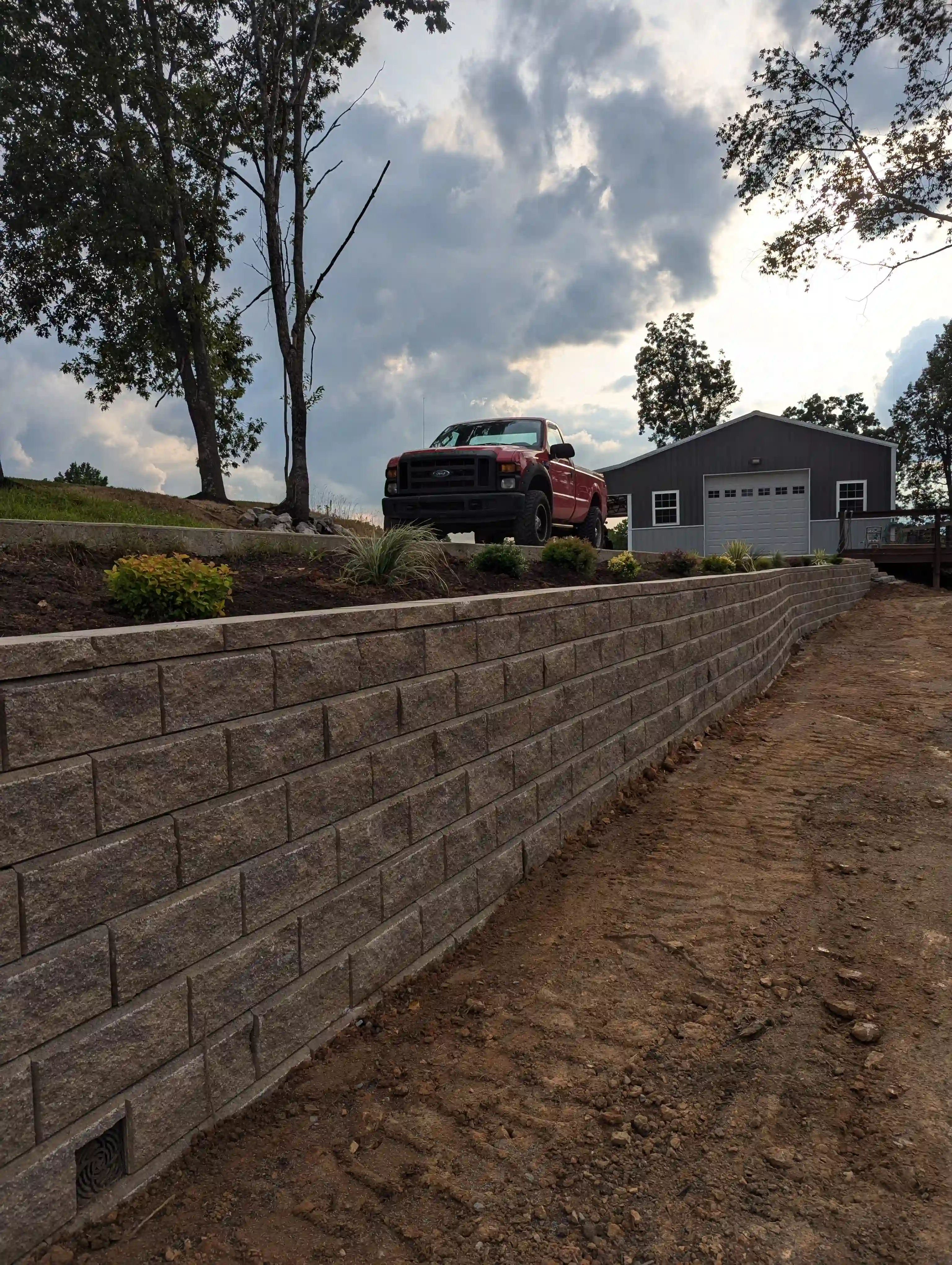 close up of a retaining wall holding up a driveway with a small planter bed on the side