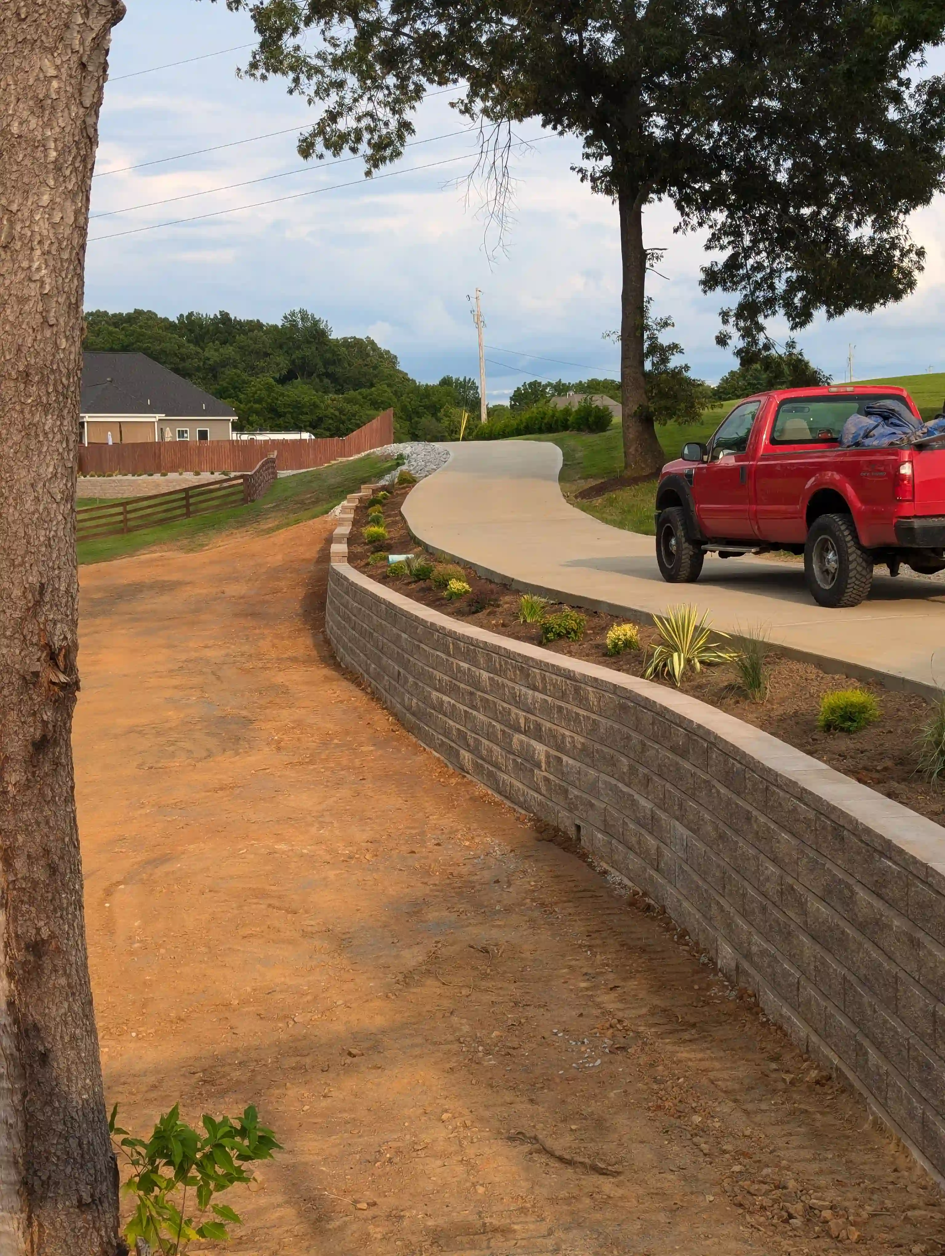 retaining wall, garden bed, and a driveway with a red truck