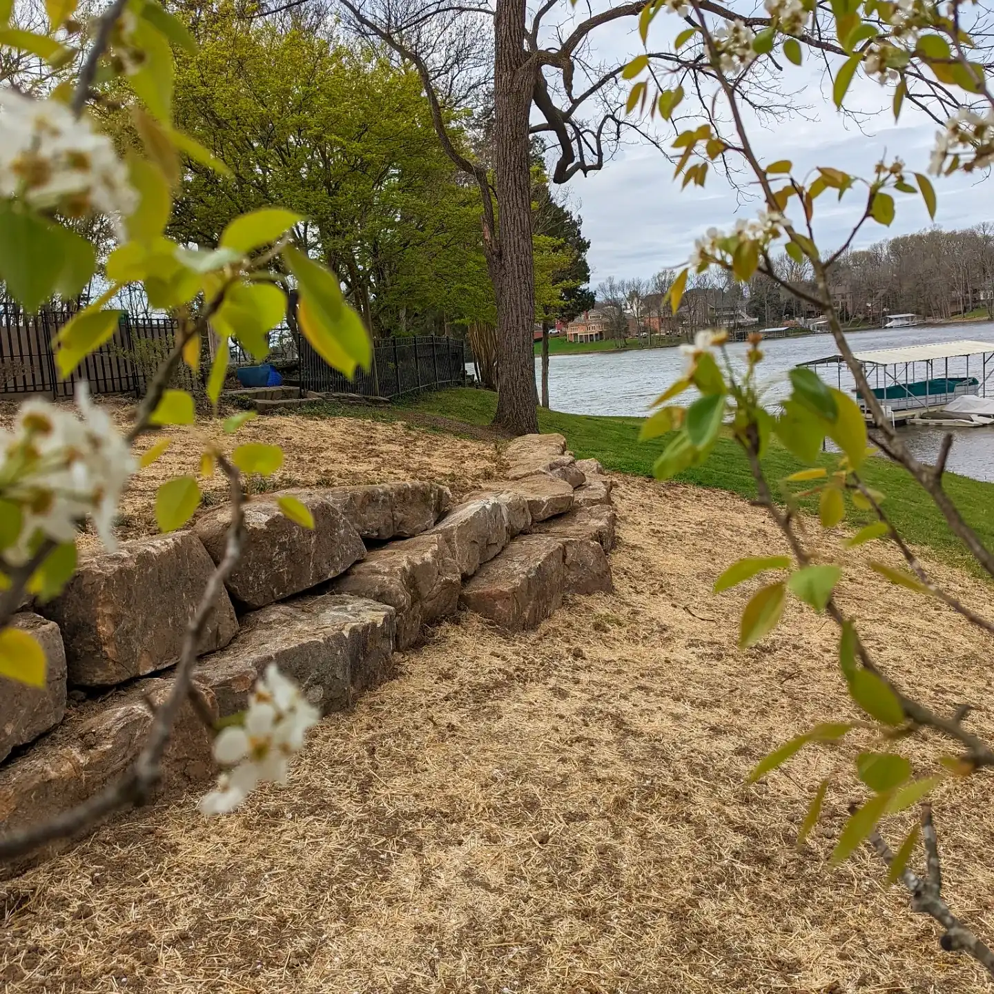 large natural stone retaining wall seen from behind a bush