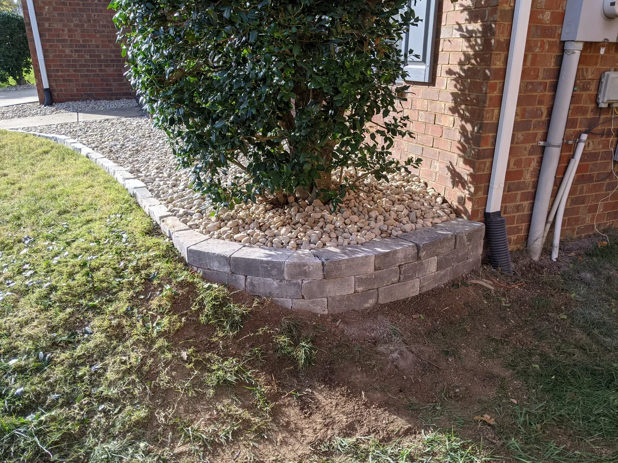 brick retaining wall with gravel bed and shrubs