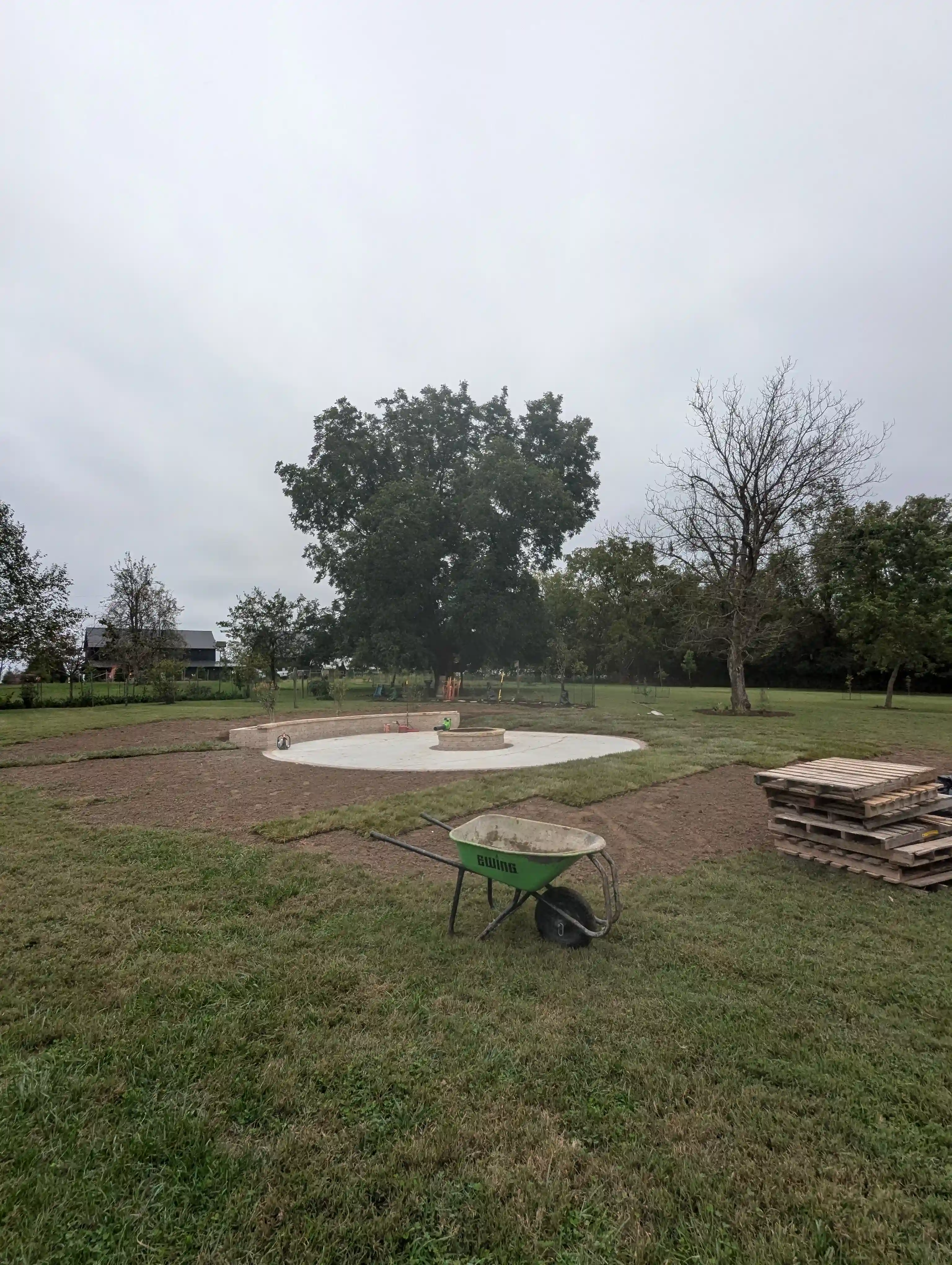 a large backyard area with a wheelbarrow and pallets being used to lay new sod