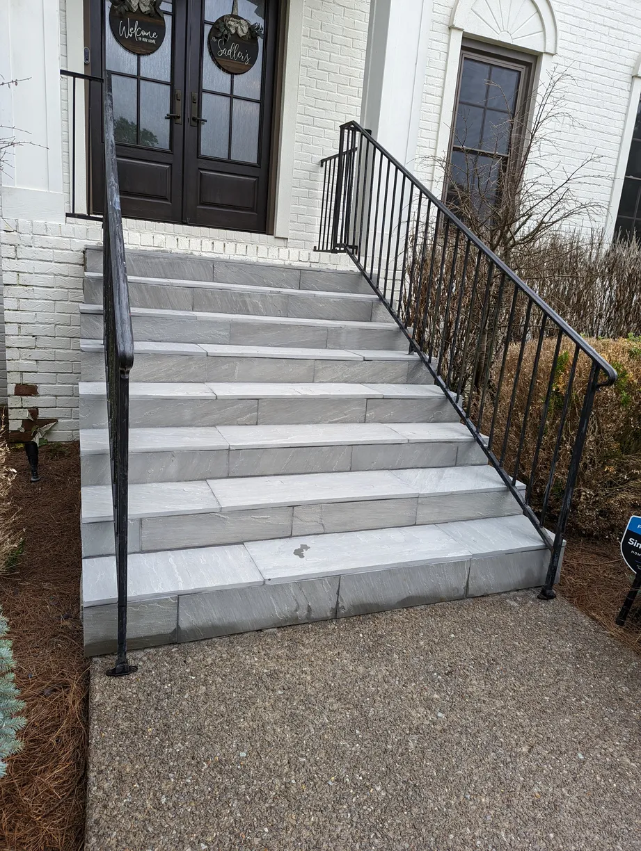 smooth stone steps leading to the front of a white home with a black door