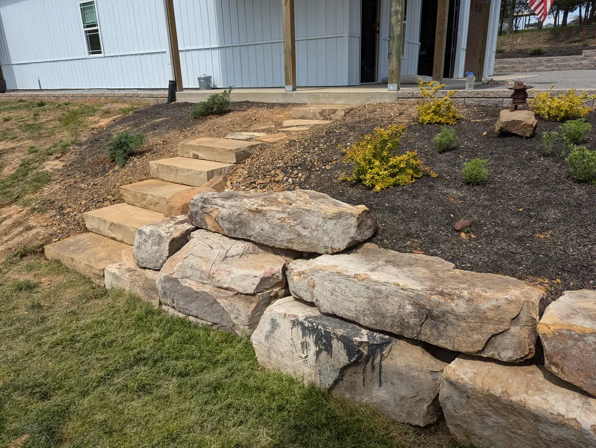 steps leading through part of a retaining wall that is using large natural boulders